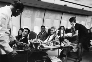 A steward and stewardess serving first-class passengers with drinks and refreshments on board a Boeing 747. (Photo by Fox Photos/Getty Images)